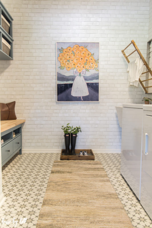 A small bench in the mudroom and a neutral rug in the room as well.