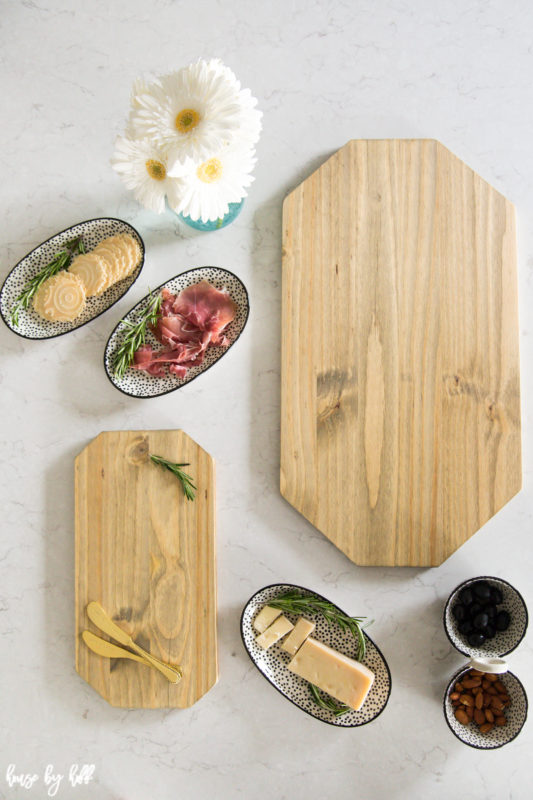 Two charcuterie boards on the counter with white flowers, and small oval bowls filled with meats and cheese.