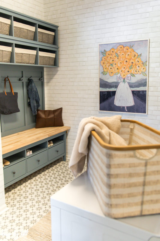 The blue bench and storage and a basket on the washing machine.