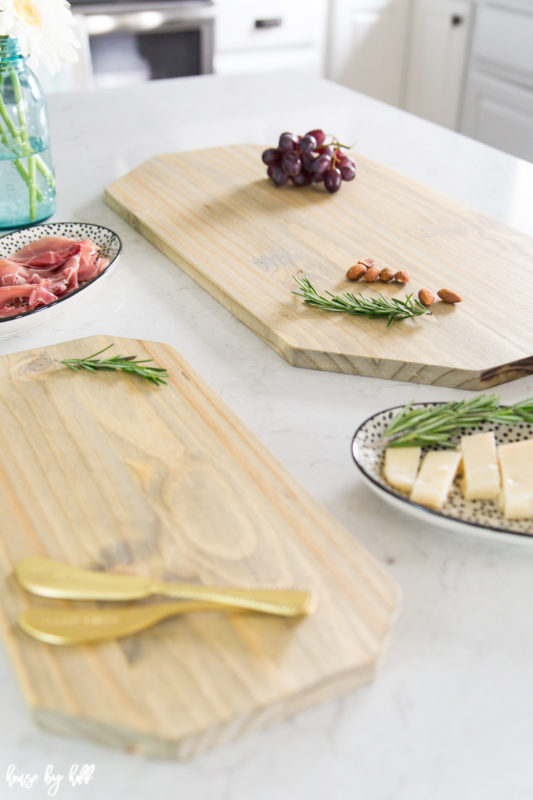 Grapes, rosemary, and gold knives on the wooden boards.
