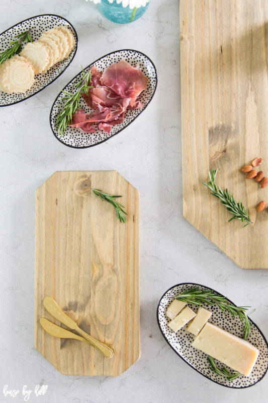Wooden charcuterie boards, meat, cheese, and crackers on the counter.