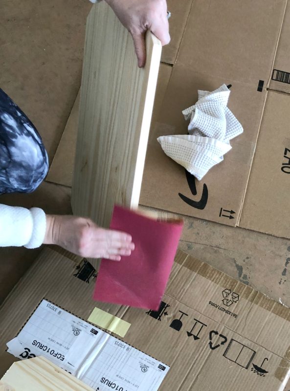 Sanding the cut piece of wood.