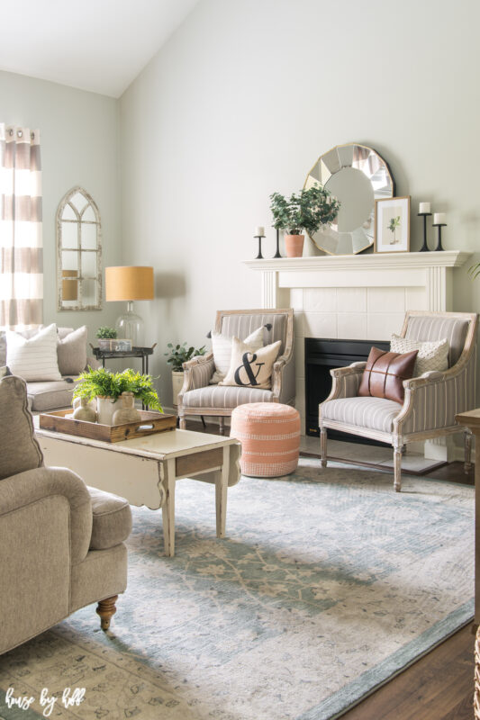 Beautiful Living Room with Blue Vintage Rug, French Armchairs, and Round Mirror