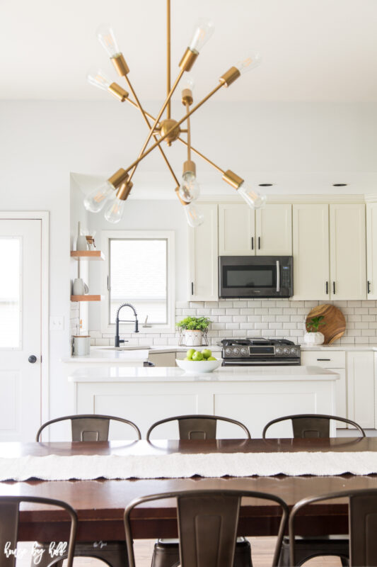 Renovated Kitchen and Eating Area with Modern Chandelier, White Subway Tile and Open Shelving.