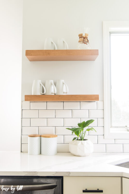 Oen shelving is in the kitchen with cups on it.