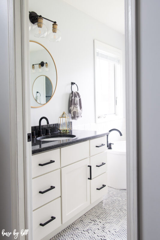 A white and black bathroom with a round mirror.