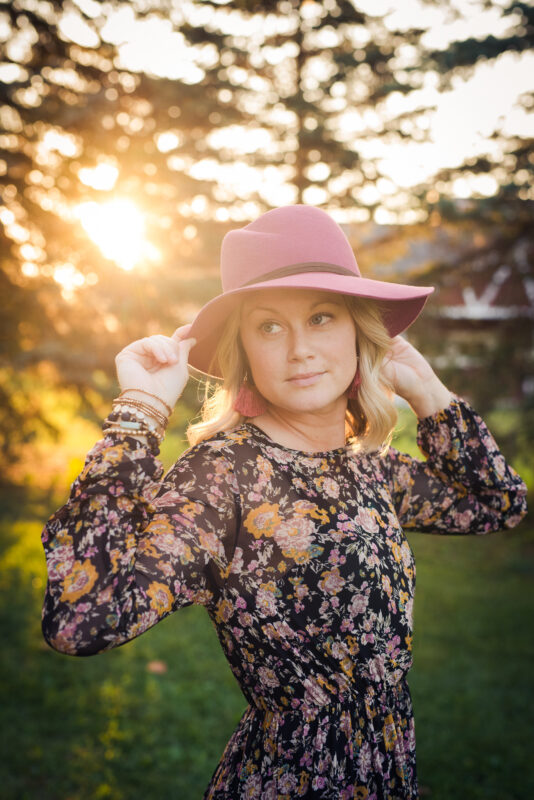 April in a dress holding her pink hat.