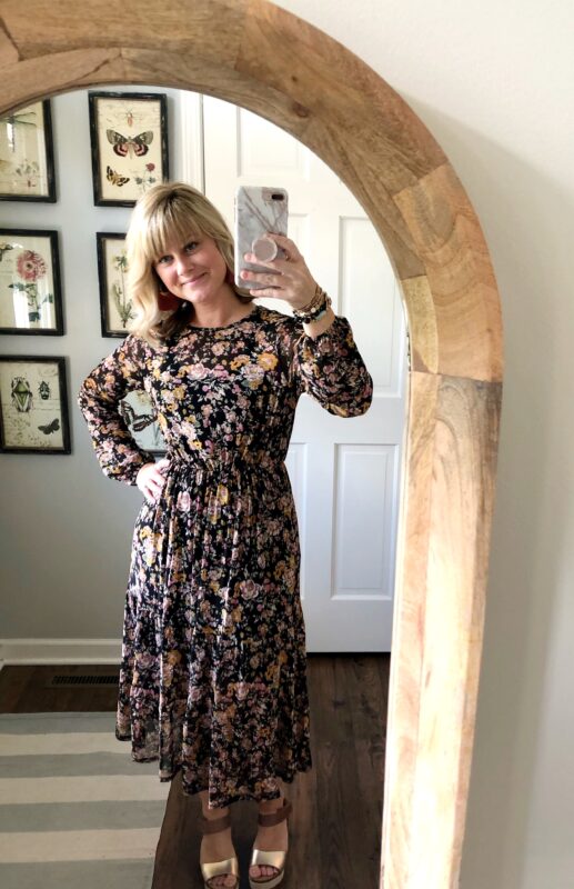 April taking a selfie in the mirror wearing a floral dress.