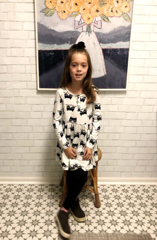 Aprils daughter posing in a black and white dress in front of a picture of a woman holding a bouquet.