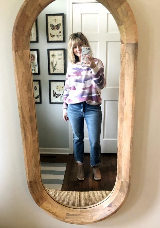 April in jeans, a pink, white and purple sweatshirt, taking a selfie.