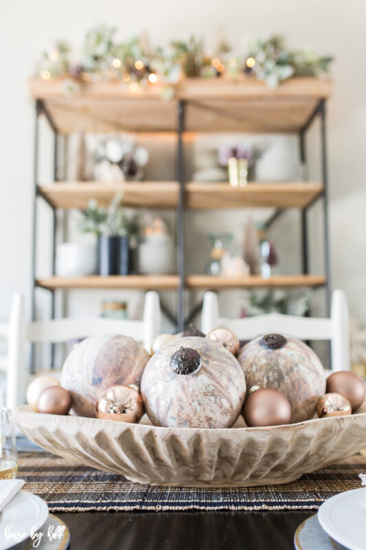 Rose Gold Ornaments in Wooden Bowl in the center of the table.