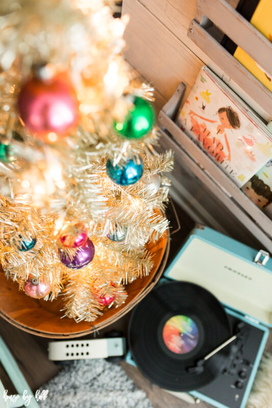 The Christmas tree in the corner by the books.