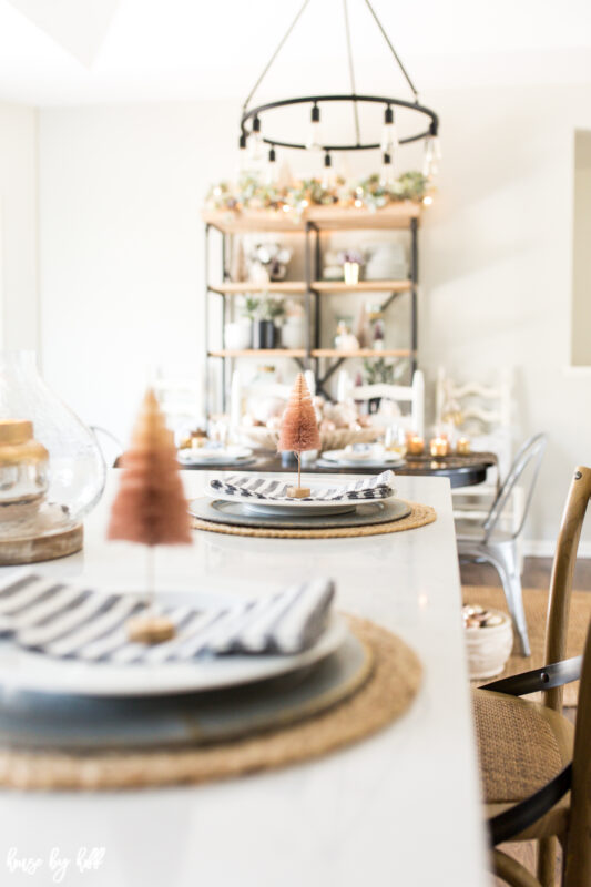 Pink Bottle Brush Trees on Place Settings with Striped Napkins are on the table in the dining room.