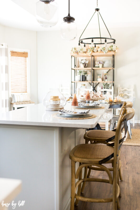 Two chairs are at the kitchen island that has a place setting for two.