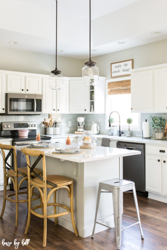 A white and gray kitchen with a White Island decorated with subtle pink.