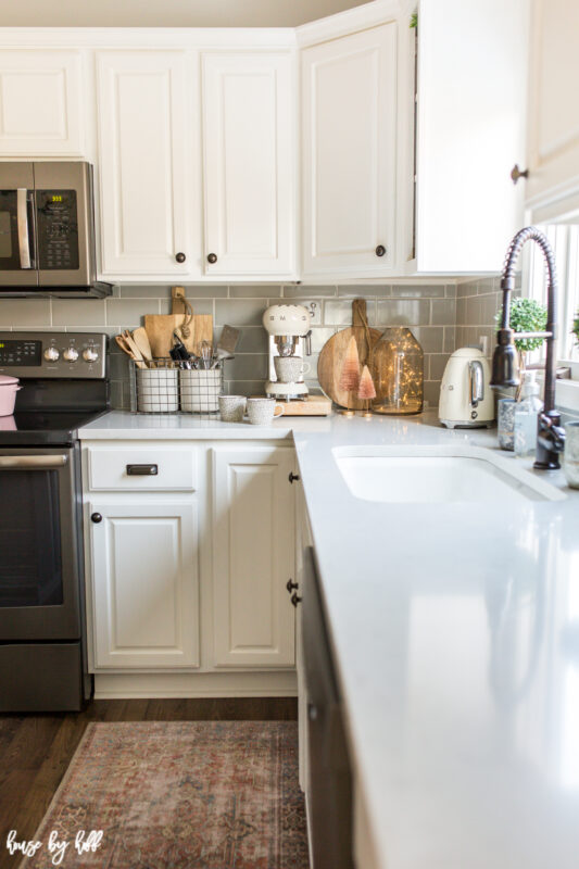 The large white farmhouse sink in the kitchen with a pink rug in front of it.