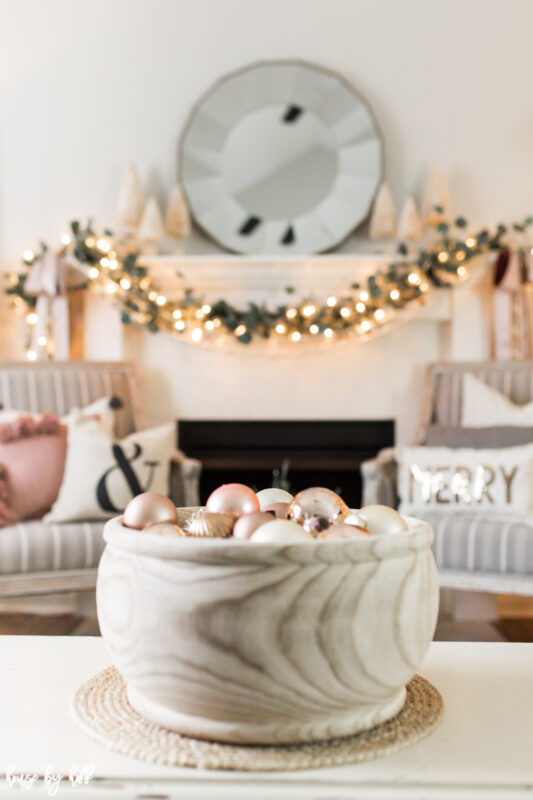 There is a wooden bowl filled with Christmas ornaments.