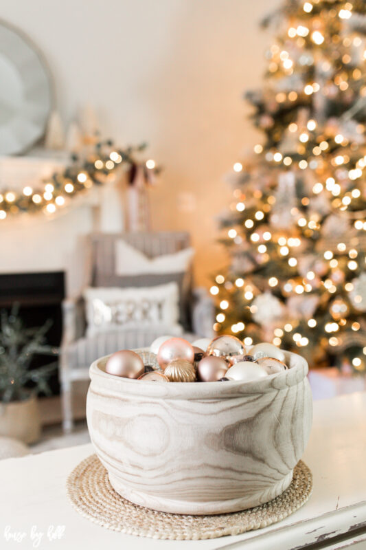 The wooden bowl on the table filled with Christmas ornaments.