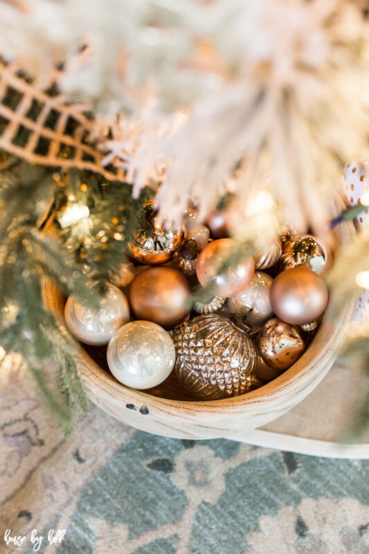 Big Wooden Bowl with Rose Gold and Cream Ornaments beside the Christmas tree.