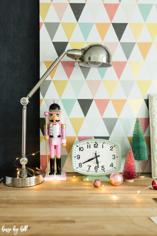 A vintage looking clock and bottle brush trees is beside the desk lamp.