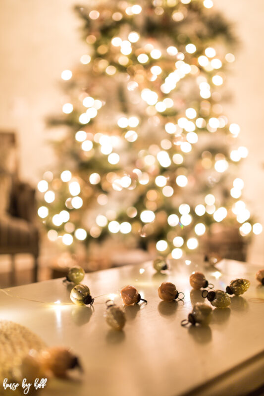 Vintage ornaments are on the table beside the tree.