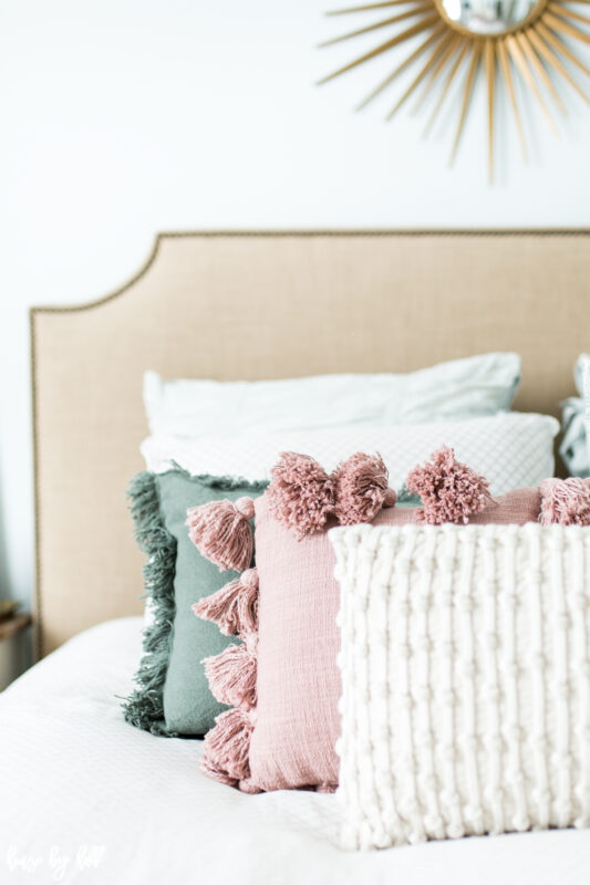 Upholstered beige headboard with tasseled throw pillows