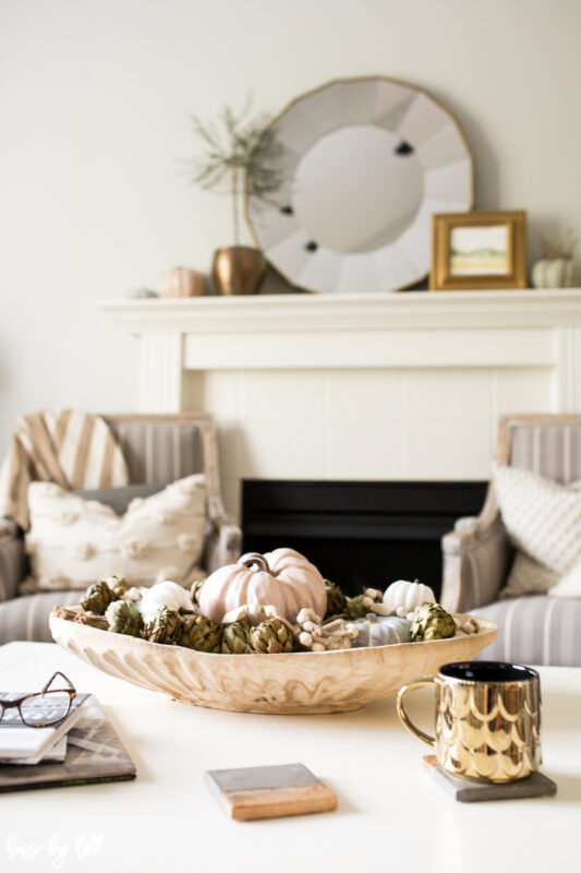 Neutral fall pumpkins on white coffee table with gold mug