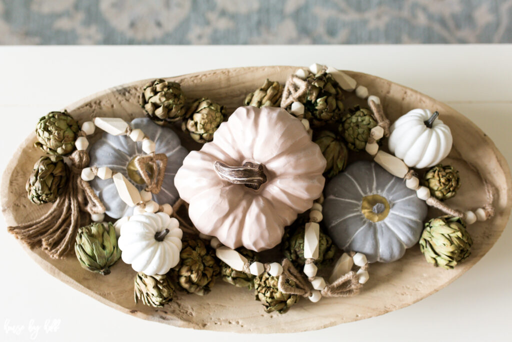 Pumpkin and artichoke centerpiece with wood beads in acacia bowl