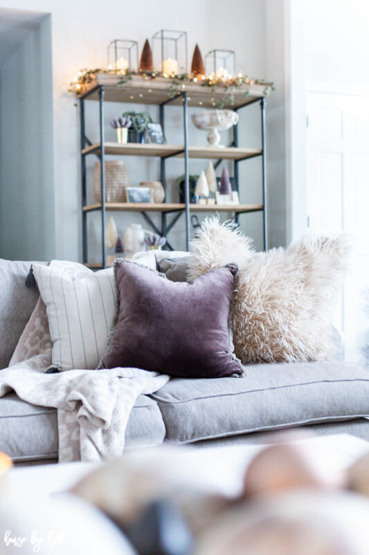 Open Shelves with Holiday Decor Behind Neutral Couch