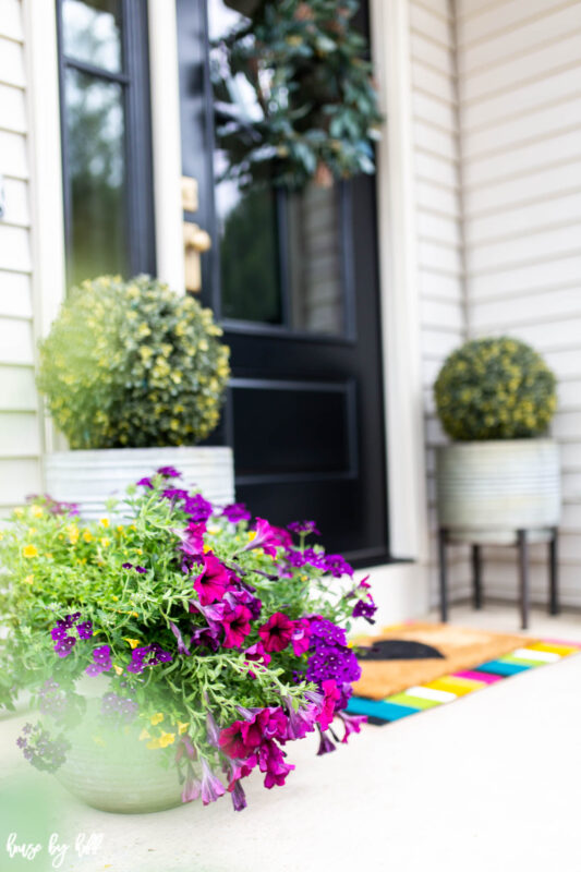 Brightly colored flowers and mat on front stoop