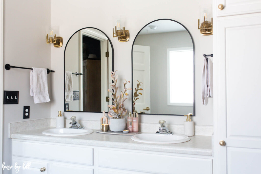 Brass Sconces and Black Arched Mirrors in Bathroom