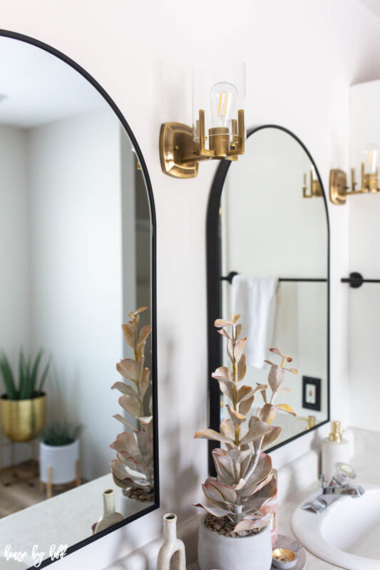 Brass Sconces and Black Arched Mirrors in Bathroom