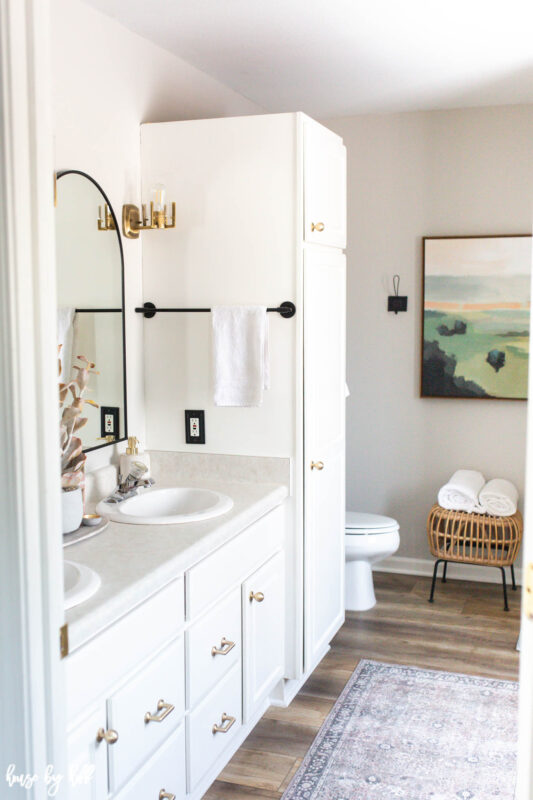 White Bathroom Cabinets with Vinyl Plank Floor and Brass and Black Finishes