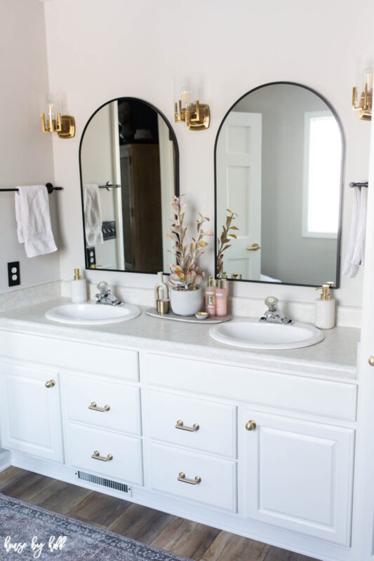 Master Bathroom With Vinyl Plank Floor, White Cabinets, and Brass Hardware
